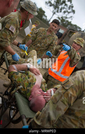 Warrant Officer Class 2 Bernadette Serong, Firma Sergeant Major 1. chirurgischen Gesellschaft, 2. Allgemeine Gesundheit Bataillon in Brisbane Australien gibt Anweisungen für Ihr Team beim Verschieben einer simulierten Unfall auf einer Bahre ProMIL 215 Warenkorb während einer Messe Unfallversicherung Übung an Williamson Airfield, Shoalwater Bay, Queensland Australien am 8. Juli 2017 während der Übung Talisman Sabre 2017. Übungen wie TS 2017 geben realistische, einschlägige Ausbildung notwendig, regionale Sicherheit, Frieden und Stabilität zu gewährleisten. Stockfoto