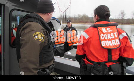 Ein Fischer auf dem Columbia River zeigt Schwimmwesten zu einem Clatsop County Sheriff's Deputy und Küstenwache lt Adriana Gaenzle während einer Dual-Agentur Strafverfolgung Patrouille durch die Offiziere von der Coast Guard Sektor Columbia River durchgeführt und das Büro der Clatsop County Sheriff's, 4. März 2017. Personal von der Coast Guard Sektor Columbia River Durchsetzung regelmäßig gemeinsam mit Abgeordneten von Office die Clatsop County Sheriff's die Sicherheit der Öffentlichkeit zu gewährleisten, während sie auf dem Wasser. Foto mit freundlicher Genehmigung der US-Küstenwache Sektor Columbia River. Stockfoto