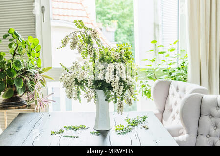 Schöne Blumen Strauß mit Blossom acacia Niederlassungen in weiße Vase auf dem Tisch im Wohnzimmer am Fenster. Interior Design und Ideen. Noch immer leben Stockfoto