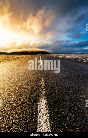Island, Nordeuropa. Eine gepflasterte Straße mit dramatischen Himmel Stockfoto