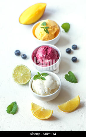 Drei verschiedene Früchte und Beeren Eis auf weißem Hintergrund, kopieren. Gefrorener Joghurt oder Eis mit Zitrone, Mango, Blaubeeren - gesunde Sommer Stockfoto