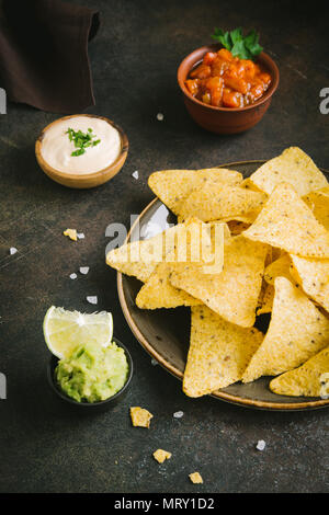 Nachos Chips und verschiedenen dip-Saucen. Tortilla Mais nachos Chips mit Salsa, geschmolzenem Käse und Guacamole, mexikanische Snacks. Stockfoto