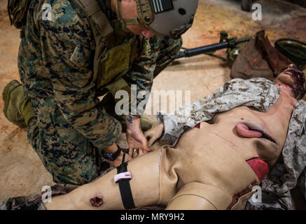 Ein Marine mit 3 Reconnaissance Bataillon, 3rd Marine Division, III Marine Expeditionary Force gilt ein stauschlauch bei einem simulierten Unfall während der Tactical Combat Casualty Care Kurs an der Taktischen medizinische Simulation Center, Camp Hansen, Okinawa, Japan, 13. Juli 2017. Die Marines abgeschlossen eine praktische Anwendung Teil des Kurses, der mit der Anwendung der medizinischen Versorgung in einer Bekämpfung der Umgebung bestand. (U.S. Marine Corps Foto von Lance Cpl. Andy Martinez) Stockfoto