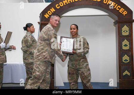 Command Sgt. Maj. Larry D. Godsey mit einer Zeit, 1.BATAILLON, 138 Infanterie Regiment, Missouri Army National Guard, präsentiert Sgt. Marlene Vazquez, 3. Medizinischen Command-Deployment unterstützen, mit einem noncommissioned officer Zertifikat an einem NCO Induktion Zeremonie am Lager als Sayliyah, Katar, 1. Juli 2017 statt. 38 U.S. Army Central Soldaten der 3. Medizinischen Command-Deployment zugewiesen sind, unterstützen, 1 Theater Sustainment Command und 1 Mrd. des Missouri Army National Guard, 138 Inf. Regt. an der Zeremonie teil. (U.S. Armee Foto von Vincent Cummings) Stockfoto