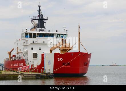 US Coast Guard Cutter Mackinaw Mauren in Cleveland Harbour, 12. Juli 2017. Die Cleveland Hafen West Pierhead Leuchtturm ist im Hintergrund sichtbar, westlich von Mackinaw. (US Coast Guard Foto von Petty Officer 3. Klasse Brian McCrum) Stockfoto