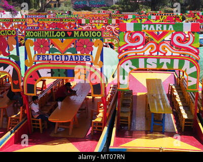 XOCHIMILCO, MEXIKO IM MÄRZ 2018: Farbenfrohe mexikanische Boote mit Frauen namen an schwimmenden Gärten in warmen, sonnigen Wintertag. Stockfoto