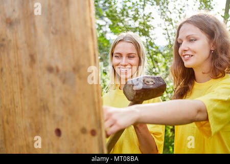 Zwei Frauen Teamarbeit mit vorschlaghammer in einem Team building Workshop Stockfoto