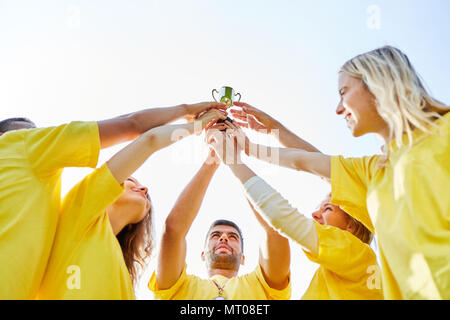 Erfolgreiche Siegermannschaft mit Pokal zusammen feiern im Teambuilding Event Stockfoto