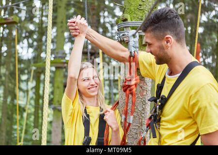 Junges Paar gratuliert beim Klettern in einem Kletterkurs im Hochseilgarten Stockfoto