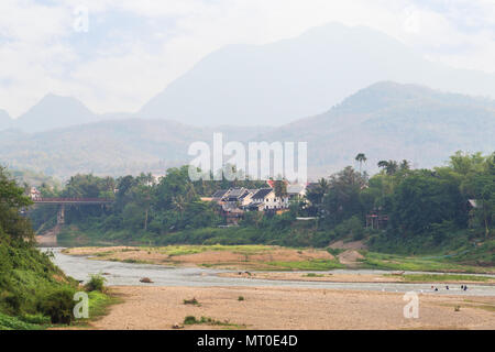 Blick auf den Fluss Nam Khan bei Ebbe und üppigen Ufer in Luang Prabang, Laos, an einem sonnigen Tag. Stockfoto