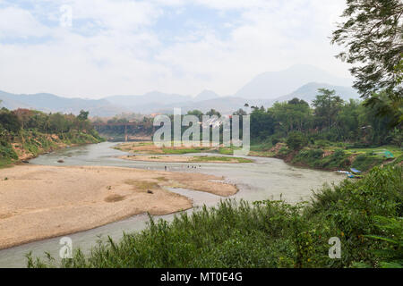 Blick auf den Fluss Nam Khan bei Ebbe und üppigen Ufer in Luang Prabang, Laos, an einem sonnigen Tag. Stockfoto