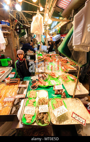 Indoor Omicho Ichiba, Omicho Markt, dem größten Markt mit frischen Lebensmitteln in Kanazawa, Japan. Frische Meer - Fisch Stall mit jungen Helfer stehen, Blickkontakt. Stockfoto