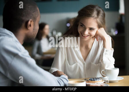 Glückliche junge interracial Paare flirten Reden halten sich an den Händen in Stockfoto
