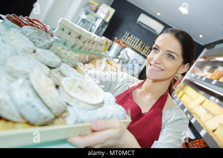 Saleslady heraus halten Käse auf dem Tablett mit Käse shop Stockfoto
