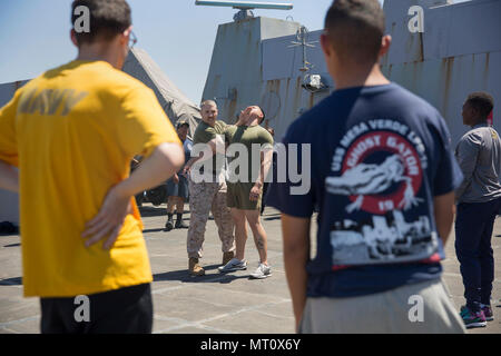 Gunnery Sgt. Arvin Manning, Personal noncommissioned Officer zuständig für die Strafverfolgung Loslösung, 24 Marine Expeditionary Unit (MEU), zeigt einen Takedown Technik auf Lance Cpl. Leonardo Castillo, ein militärischer Polizist, während eine nicht tödliche Klasse als Teil des Master-at-arms Ausbildung an Bord des amphibious Transport dock Schiff USS Mesa Verde (LPD 19) April 15, 2017. Die 24. MEU ist mit dem Bataan Amphibious Ready Gruppe unterwegs in der Unterstützung der Maritime Security Operations und Theater Sicherheit Zusammenarbeit in den USA 6 Flotte Bereich der Operationen. Stockfoto