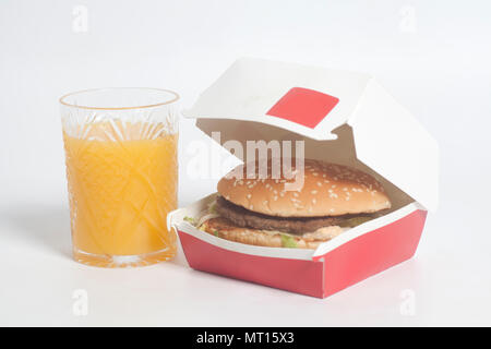 Lecker große Hamburger im Karton und Glas Orangensaft auf weißem Hintergrund Stockfoto