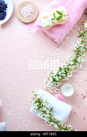 SPA. Handtuch, Meersalz und Seife. Rosa Hintergrund und Blumen. Für Text platzieren. Vertikale Foto. Stockfoto