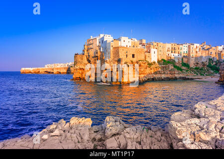 Polignano a Mare, Apulien, Italien: Sonnenuntergang in Cala Paura Golf mit Bastione di Santo Stefano und Lama Monachile Strand Stockfoto