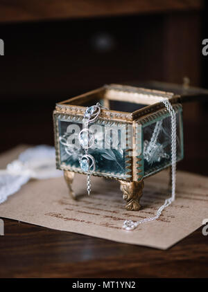 Schöne vintage Glas Hochzeit Schmuck Box mit etwas Blau (Ohrringe) auf der Hochzeit Einladung Hintergrund. Stockfoto