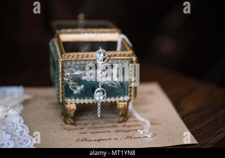 Schöne vintage Glas Hochzeit Schmuck Box mit etwas Blau (Ohrringe) auf der Hochzeit Einladung Hintergrund. Stockfoto