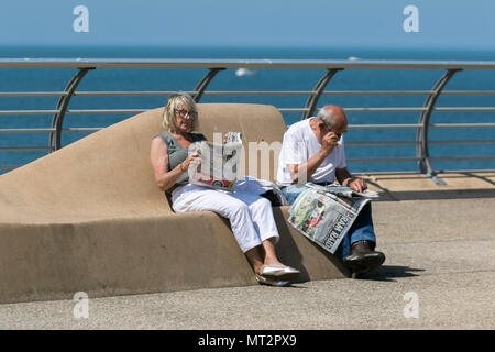 Sitzende paar Zeitung lesen in der Sonne in Blackpool, Lancashire. UK Wetter. 28 Mai, 2018. Hellen sonnigen Start in den Tag an der Küste wie Urlaubern und Touristen Annehmlichkeiten und Attraktionen an der Strandpromenade im warmen Sonnenschein. Credit: MediaWorldImages/AlamyLiveNews Stockfoto