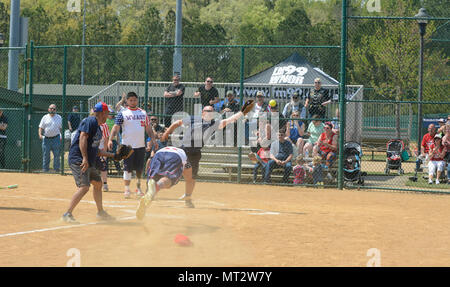 Ein verwundeter Krieger Amputee Softball Team rutscht in die Home Plate während des WWAST Softball Spiel gegen die Newport News Polizei und Feuerwehr in Newport News, Virginia, 15. April 2017. Die WWAST Spieler hosten auch Softball ein Kids Camp zu erziehen und zu inspirieren, Kinder, sehen sich denselben Herausforderungen gegenüber. Stockfoto