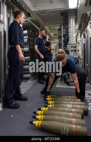 170719-N-ZW 825-660 CORAL SEA (19 Juli 2017) Matrosen an Bord der Arleigh-Burke-Klasse geführte Anti-raketen-Zerstörer USS Sterett (DDG104) Line up Umläufe für die 45 5 MK-inch Gun im tiefen Magazin während einer Naval surface Fire Support Übung als Teil der Talisman Sabre 17. Die Übung soll die Flex "Up-Gunned Expeditionary Strike Group (ESG)"-Konzept mit Kreuzer und Zerstörer Vermögenswerte der ESG zu schützen. Talisman Säbel ist eine Biennale USA und Australien bilateralen Ausübung gehalten vor der Küste von Australien gedacht, um die Interoperabilität zu erreichen, und die USA und Australien Bündnis stärken. (U Stockfoto