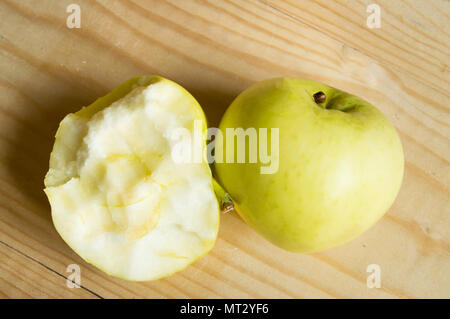 Reif Grün gebissen und ganzen Apfel auf einer hölzernen Hintergrund. Stockfoto