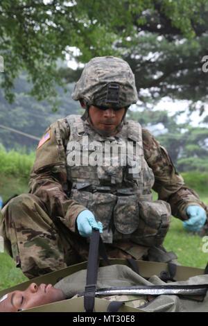 Spc. Jorge H. Garatecarabajo, ein mit Rädern versehener Fahrzeug Mechaniker 579 unterstützt Unternehmen, 6 Battalion, 37th Field Artillery Regiment, 210Th Field Artillery Brigade, 2 Infanterie Division/ROK-US kombinierte Geschäftsbereich zugeordnet sind, sichert ein Patient in einem Skedco im Camp Casey, Südkorea, 21. Juli 2017. Im Rahmen der Bekämpfung der Lebensretter Kurs, Soldaten gehandelt, realen Szenario, einen Unfall während einer Patrouille und ärztliche Hilfe. (U.S. Armee Foto von Sgt. Michelle U. Blesam, 210Th FA BDE PAO) Stockfoto