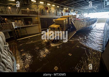 170724-N-ZL 062-051 CORAL SEA (Juli 24, 2017) ein Marine Fahrzeug fährt Landing Craft utility 1666 in der gut Deck des amphibious Transport dock USS Green Bay LPD (20) Nach der Talisman Sabre 17. Talisman Säbel ist eine Biennale USA - Australien bilaterale Übung gehalten weg von der Küste von Australien gedacht, um die Interoperabilität zu erreichen und den USA - Australien Bündnis stärken. (U.S. Marine Foto von Mass Communication Specialist 3. Klasse Sarah Myers/Freigegeben) Stockfoto