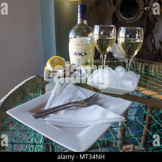 Lüderitz, Namibia - 08 Juli 2014: frische Austern, Eis und Weißwein, weiße Platten auf Glas Tisch, Shearwater Oyster Bar Stockfoto