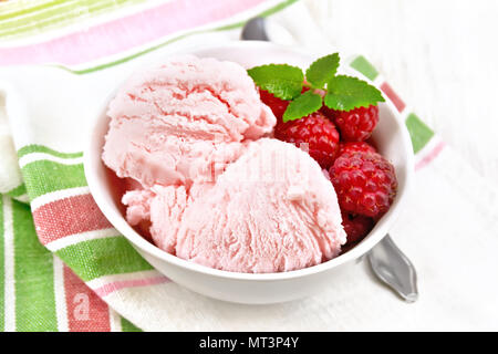 Eis crimson mit Himbeeren, Beeren und Minze in weiße Schüssel, einen Löffel auf dem Handtuch auf dem Hintergrund der Holzplatte Stockfoto