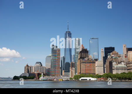 Die Skyline von New York mit Blick auf den Battery Park, durch das One World Trade Center unter einem blauen Himmel beherrscht. Stockfoto