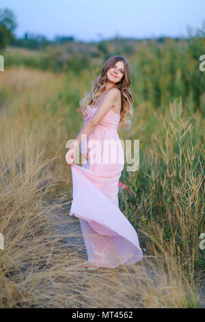 Schwangere junge Frau tragen rosa Kleid in der Steppe Hintergrund. Stockfoto