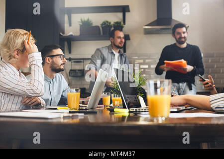 Gruppe der kreativen Mitarbeitern am Küche Brainstorming. Geschäft Leute zusammen arbeiten und mit Laptops. Junges Team von Managern macht große Unternehmen Stockfoto
