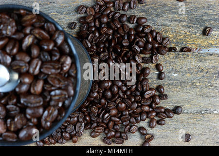 Geröstete Kaffeebohnen in einer kaffeemühle von Hand. Und Fokus auf gerösteten Kaffeebohnen auf einer hölzernen Hintergrund verbreiten. Stockfoto