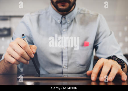 Geschäftsmanns, der auf Tablet mit Stift Bärtigen. Geschäftsmann Hände Arbeiten am Laptop. Konzept der digitalen Touchpad auf hölzernen Tisch Stockfoto