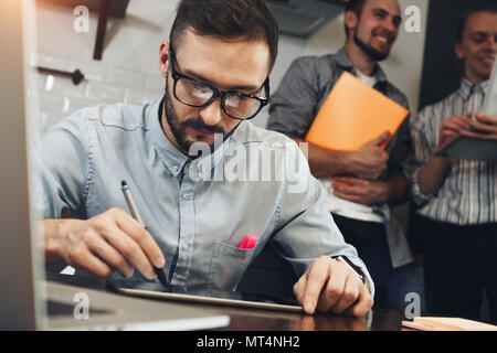 Nahaufnahme einer modernen Geschäftsmann mit Tablet Computer mit finanziellen Daten zu arbeiten. Teamarbeit. Junge Unternehmer mit neuen startup Projekt Stockfoto