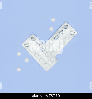 Weiße Pillen und Blisterpackung auf lila pastellfarbenen Hintergrund. Pharmazeutische Industrie minimal noch Leben flach Hintergrund. Opioid-Epidemie. Stockfoto