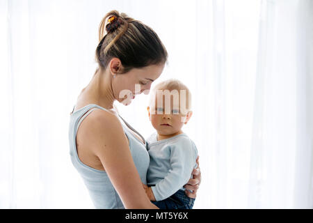 Junge Mutter, die mit Zärtlichkeit und ihr Baby Care, glücklich lächelnd, Familie Glück Konzept Stockfoto