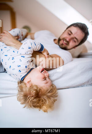 Vater mit einem Kleinkind junge Spaß haben im Schlafzimmer zu Hause vor dem Schlafengehen. Stockfoto