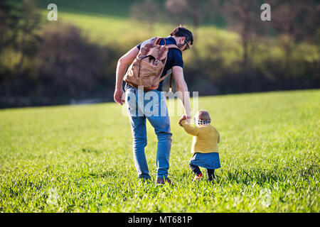 Ein Vater mit seinem Kind Tochter auf einen Spaziergang ausserhalb im Frühjahr die Natur. Stockfoto