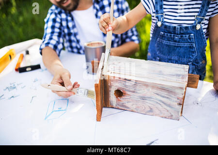 Vater mit einer kleinen Tochter außerhalb, so dass Holz Vogelhaus. Stockfoto