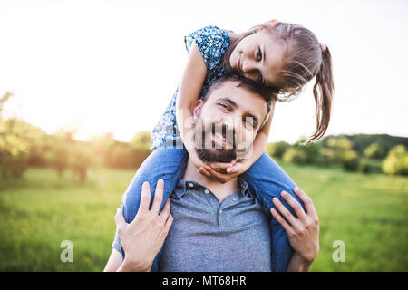 Vater einer kleinen Tochter piggyback Ride im Frühjahr die Natur. Stockfoto