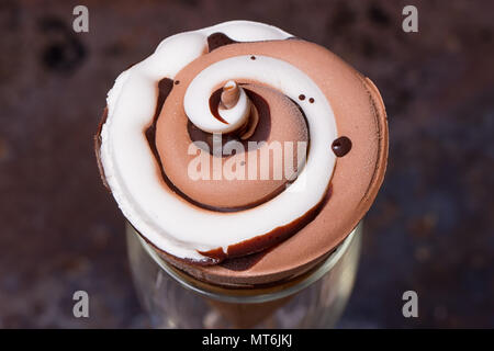 Eis in der Waffel Kegel mit Schokolade Sirup toppingn in Glas auf dunklen schwarzen Hintergrund Stockfoto