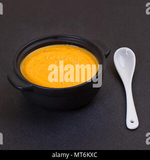 Kürbis Suppe in kleinen schwarzen Terrine auf vintage Schiefer Kreidetafel Stockfoto