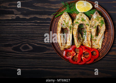 Gebratener Fisch in Ton Platte, auf dunklem Hintergrund. Stockfoto