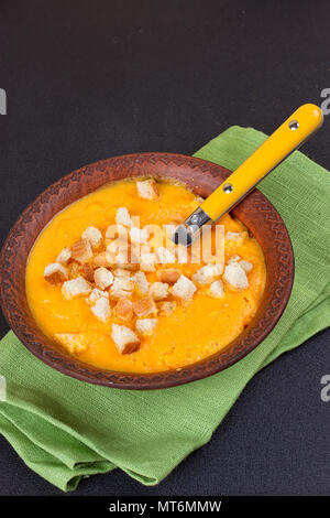 Kürbis und Karotten Suppe mit Sahne und Petersilie auf dunklem Hintergrund Stockfoto
