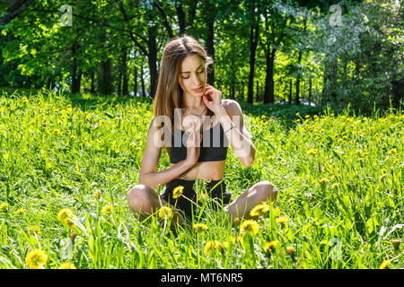 Junge, schöne Frau Sport Übungen in eine sonnige Wiese im Park Stockfoto