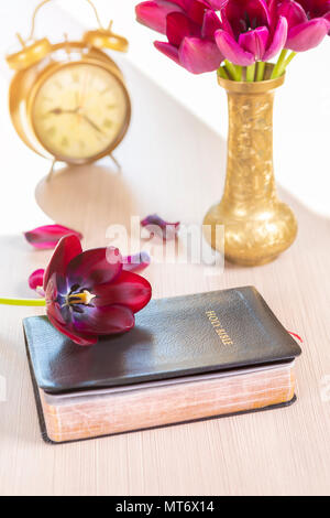 Bibel und alte Gold Wecker mit Blumen auf hölzernen Tisch Hintergrund. Fokus auf Blume über Bibel Stockfoto